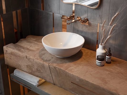 ronde keramische waskom wit in badkamer op houten badmeubel met bronze inbouwkraan