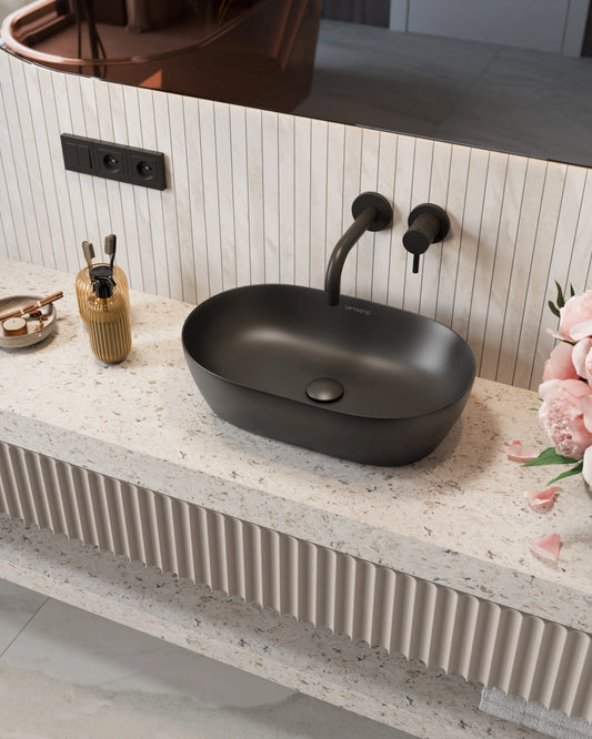Zwarte ovale keramische waskom op licht natuursteen blad met zwarte wandkraan in moderne badkamer
