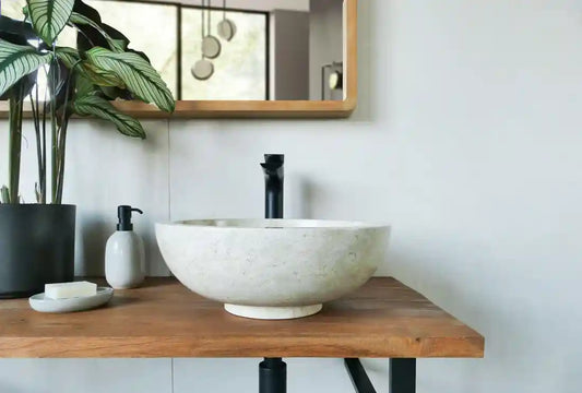 lichte ronde natuurstenen waskom op houten blad met zwarte opbouwkraan