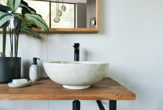 lichte ronde natuurstenen waskom op houten blad met zwarte opbouwkraan