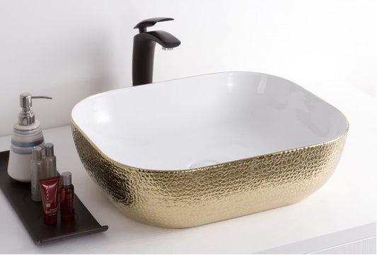 rechthoekige keramische waskom wit met goudkleurige buitenkant, opbouwmodel op wit meubel met zwarte kraan