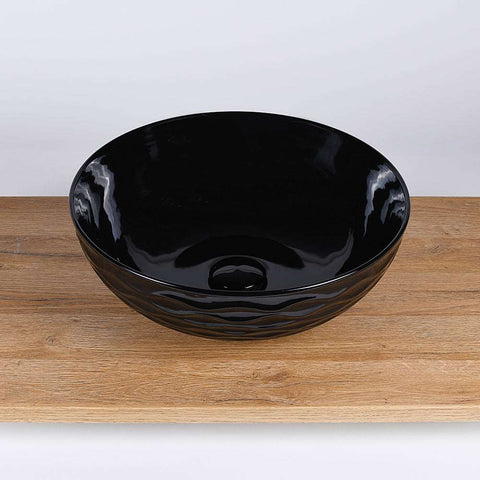 Ronde zwarte keramische waskom 42x42x14 cm als opbouwmodel voor moderne badkamer, gefotografeerd op houten blad