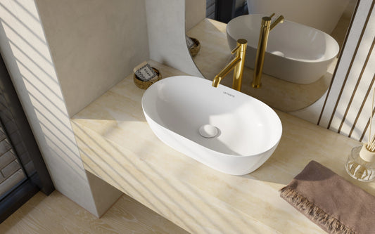 Witte ovale keramische waskom op licht natuursteen blad met gouden opbouwkraan in moderne badkamer