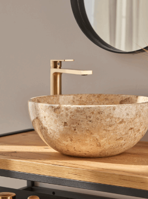 Beige ronde natuurstenen waskom 35x35x15cm met travertinlook op houten badmeubel, gecombineerd met elegante goudkleurige kraan.