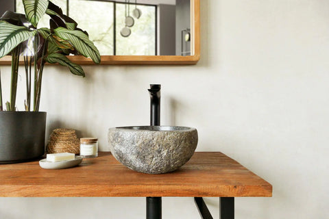 kleine grijze riviersteen waskom op blad met kraan