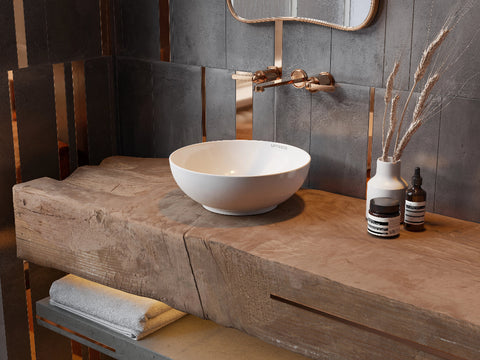 Moderne witte waskom met ronde vorm geplaatst op een rustieke houten badkamermeubel